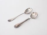 two spoons and a spoon rest on a white surface