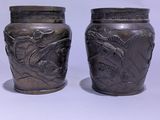 two silver vases sitting next to each other on a white surface
