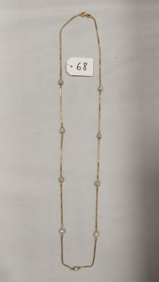 un gros plan d'un collier en or orné de perles sur fond blanc