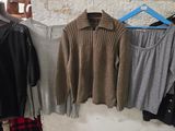 plusieurs pulls suspendus à un portant dans un magasin de vêtements