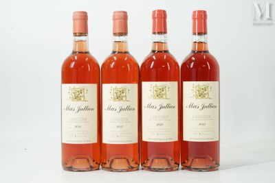 quatre bouteilles de vin sont alignées sur une surface blanche