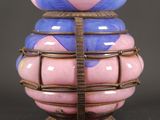 un vase rose et bleu posé sur un socle en bois