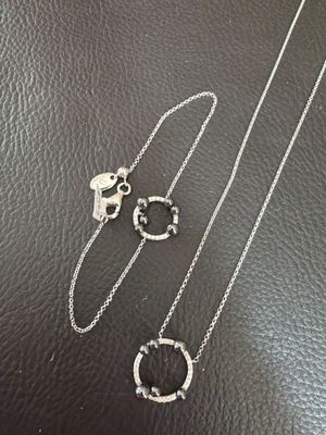 a close up of two silver necklaces on a black surface