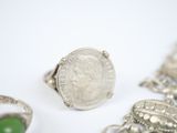 several silver rings and a silver ring with a green stone