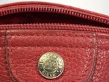 the inside of a red purse with a gold button on it