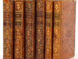 trois vieux livres posés l'un sur l'autre sur une surface blanche