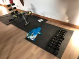 a gym room with a black mat and a pair of dumbbells