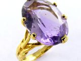 an image of a purple stone ring with gold accents on a white surface