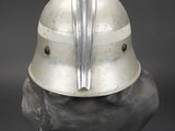 silver helmet on a black surface with a metal blade sticking out of the top of it