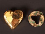 deux bijoux en or et émeraude posés sur un fond noir