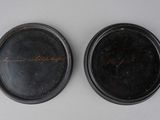 two black plates with writing on them sitting next to each other