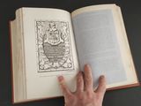 a hand that is holding an open book on a table