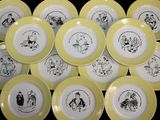 yellow and white plates with black drawings on them on a black surface