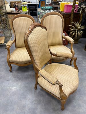 Trois chaises sont disposées dans une pièce où l'on aperçoit de nombreux meubles en arrière-plan.