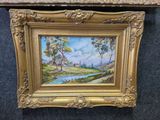 a painting of a landscape with trees and a river in a gold frame