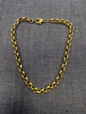 un gros plan d'un collier à chaîne dorée sur fond gris