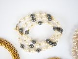 several different types of pearls and gold necklaces on a white surface