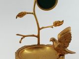 une assiette en or sur laquelle sont représentés un oiseau et un arbre