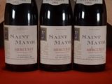 three bottles of wine are lined up on a red table