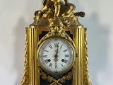 a gold clock with a statue on top of it