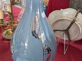 un vase bleu posé sur une table, sur laquelle se trouve une lampe