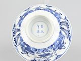 underside view of a blue and white plate on a clear stand