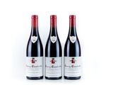 three bottles of red wine sitting on top of a white table