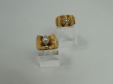pair of gold and diamond earrings on clear acrylic stand