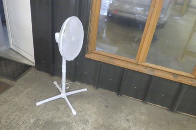 un ventilateur blanc posé sur le trottoir devant un immeuble