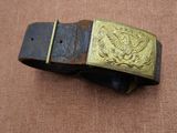une vieille ceinture avec une boucle en laiton sur un fond marron
