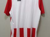 a white and red shirt hanging on a hanger on a wall