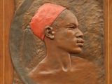 une photo d'une plaque en bronze représentant un homme portant un bandeau rouge