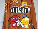 a brown jacket with m & m ' s on it hanging on a wall