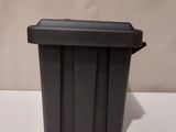black plastic trash can with lid on a white table