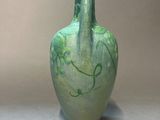 a green vase sitting on a table with a gray background
