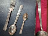 a bunch of silverware on a table with a red cloth
