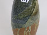a brown and green vase sitting on a white surface