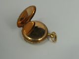 a gold pocket watch on a white surface
