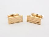 a pair of gold cufflinks on a white background