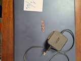 a laptop and a charger on a desk with a note attached to it