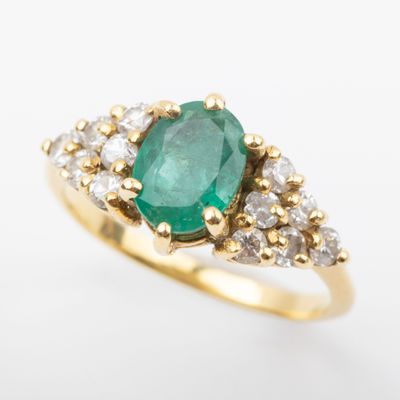 an oval emerald and diamond ring on a white background