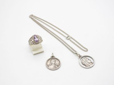a couple of silver necklaces and a coin on a white surface