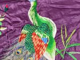 a peacock that is sitting on a purple cloth