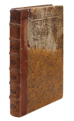 un vieux livre à la couverture brune posé sur une surface blanche