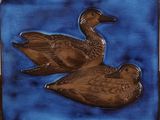 two ducks that are sitting on a blue tile