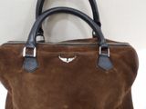 brown sued handbag with black leather handles on a white surface