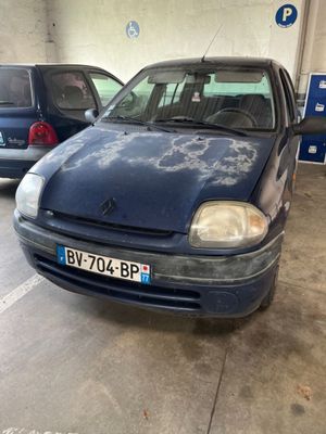 une voiture bleue garée dans un garage, avec d'autres voitures en arrière-plan