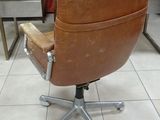 brown leather office chair on casteors in front of a wooden cabinet