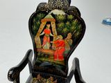 a miniature chair with a painting on the back of it