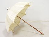 un parapluie blanc avec un manche en bois posé par terre
